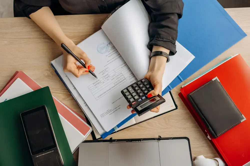 Accountant reviewing financial documents with a calculator at a desk